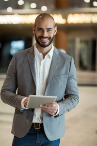 Portrait of smiling businessman using digital tablet in waiting area at airport terminal